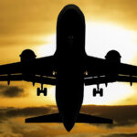 A silhouette of an airplane in front of a sunset for the article "Link Between Climate Change and Plane Turbulence Frequency"